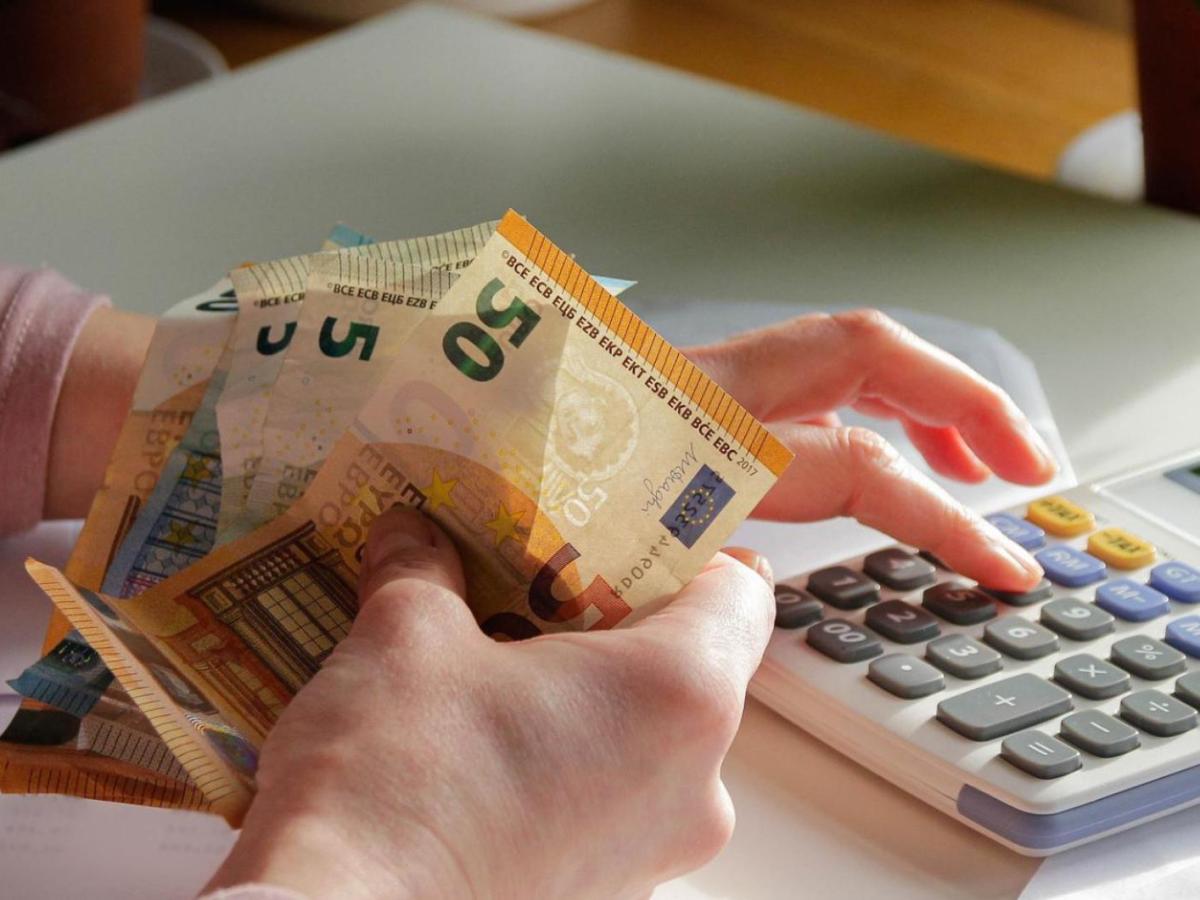 Frau h&auml;lt Geldscheine in der Hand und tippt auf einem Taschenrechner.