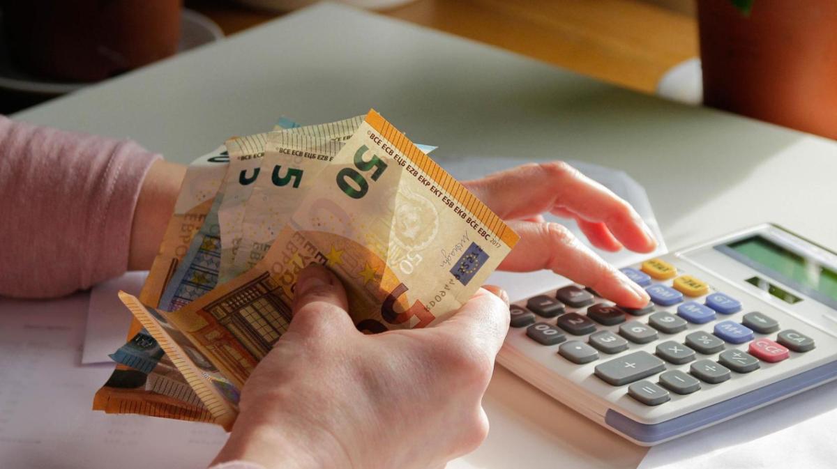 Frau hält Geldscheine in der Hand und tippt auf einem Taschenrechner.