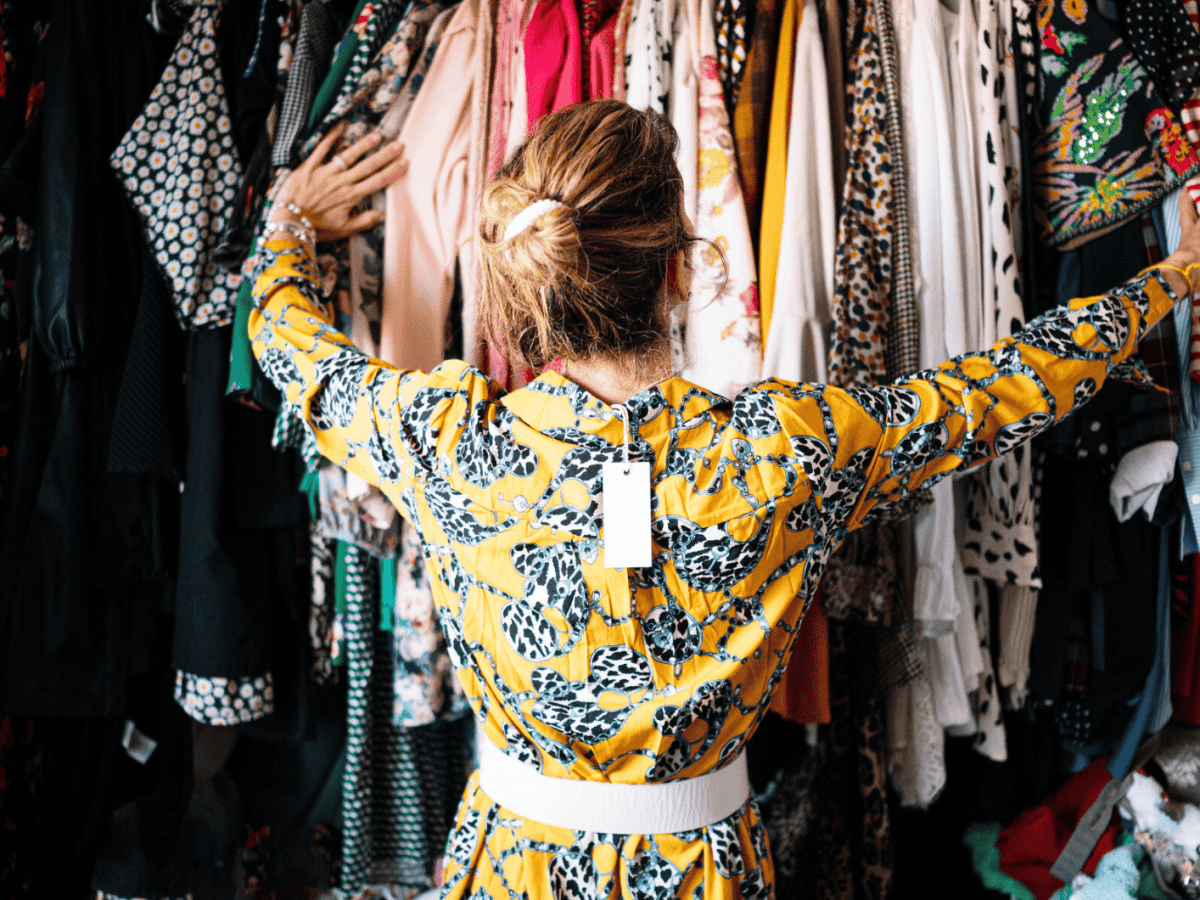 Frau in neuem Kleid stöbert durch Kleiderschrank.