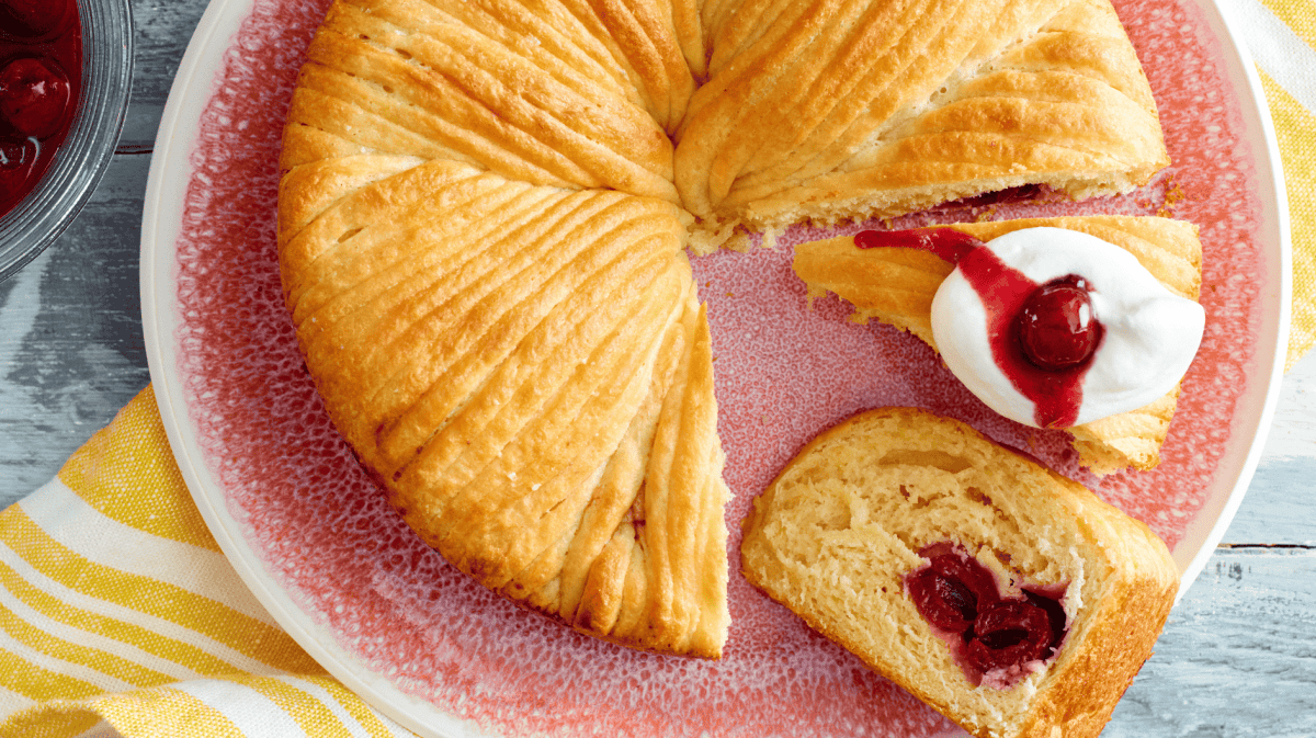 Wollknäuel Kuchen mit Kirschen auf einem rosa-farbenen Teller.