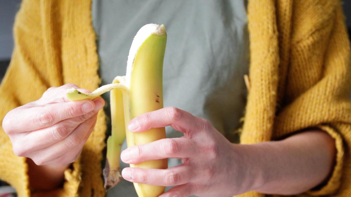 Frau schält eine Bananen.