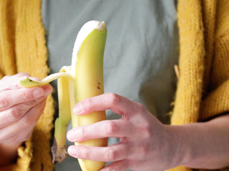 Frau schält eine Bananen.