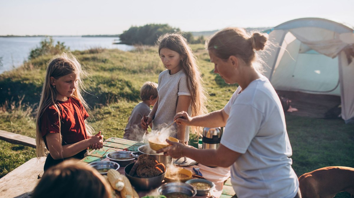 Familie auf einem Campingplatz kommt gerade zum Essen zusammen.