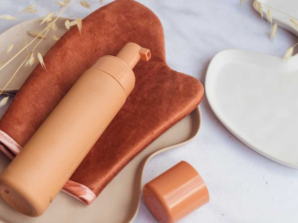 Selbstbräunerflache liegt auf einem Handschuh