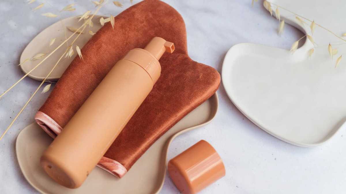 Selbstbräunerflache liegt auf einem Handschuh