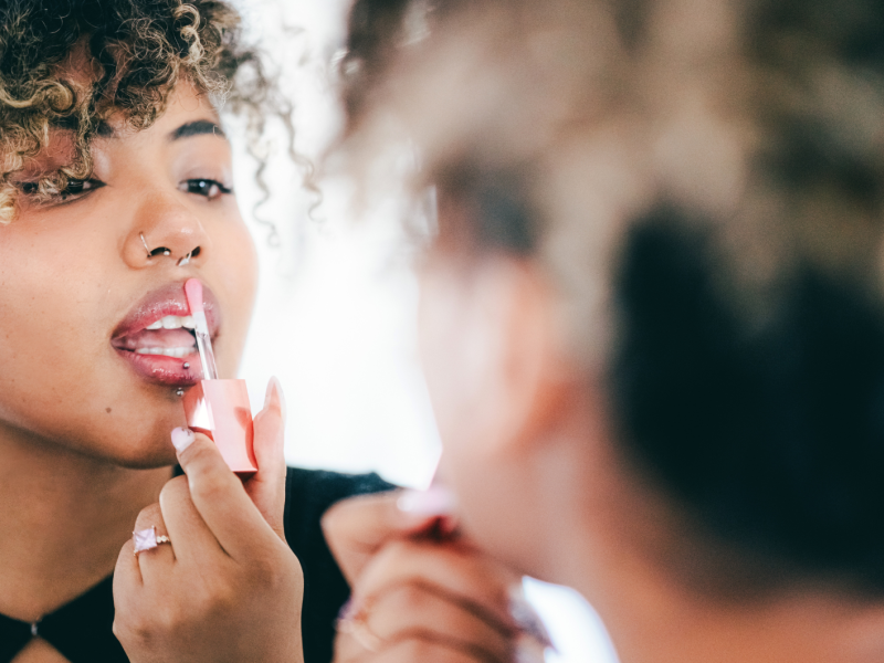 Frau trägt ihren rosafarbenen Lipgloss auf.