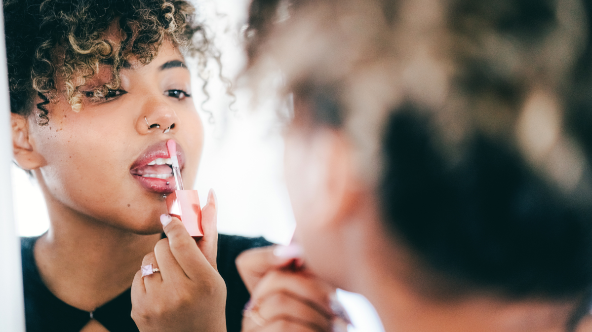 Frau trägt ihren rosafarbenen Lipgloss auf.