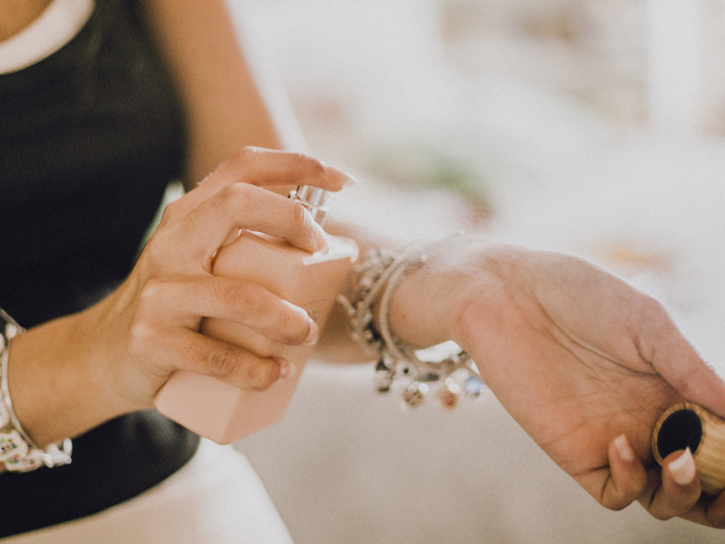 Frau, die Duft auf den Arm aufsprüht.