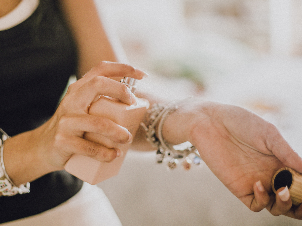 Frau, die Duft auf den Arm aufsprüht.