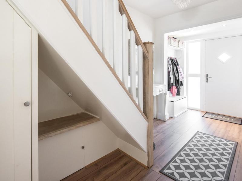 Kleiner Flur mit einer großen Treppe nach oben. auf dem Boden liegen Teppiche.