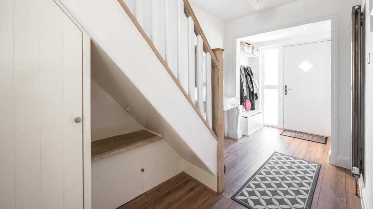 Kleiner Flur mit einer großen Treppe nach oben. auf dem Boden liegen Teppiche.