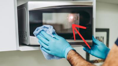 Warum haben Mikrowellentüre Punkte? Mann macht eine Mikrowelle sauber. An der Türe sind Punkte.
