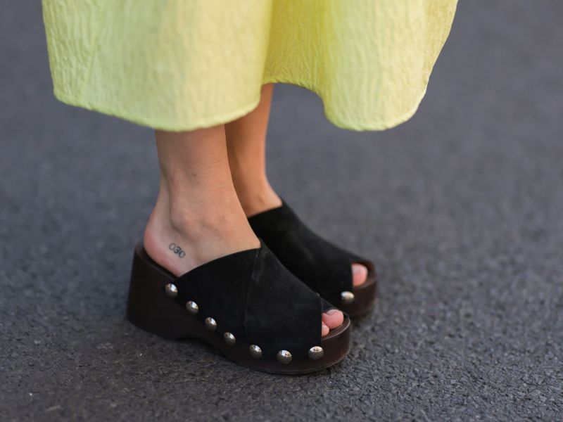 Streetstyle von Frau in gelbem Kleid und schwarzen Clogs