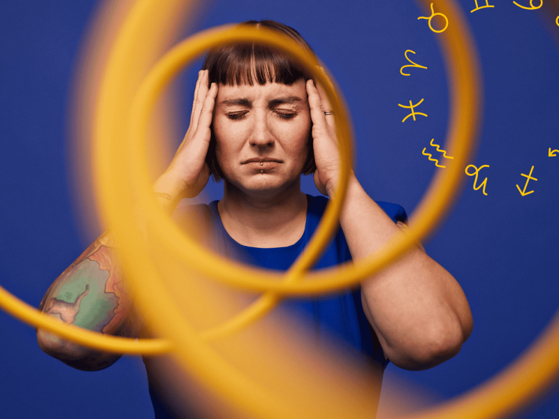 Frau vor blauem Hintergrund hinter gelber Spirale hält sich mit geschlossenen Augen den Kopf