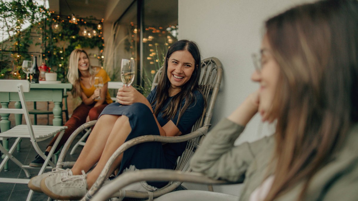 Drei Frauen sitzen im Sommer entspannt auf der Terrasse und unterhalten sich.