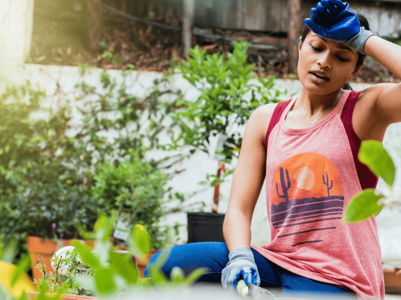Frau schwitzt bei Gartenarbeit.