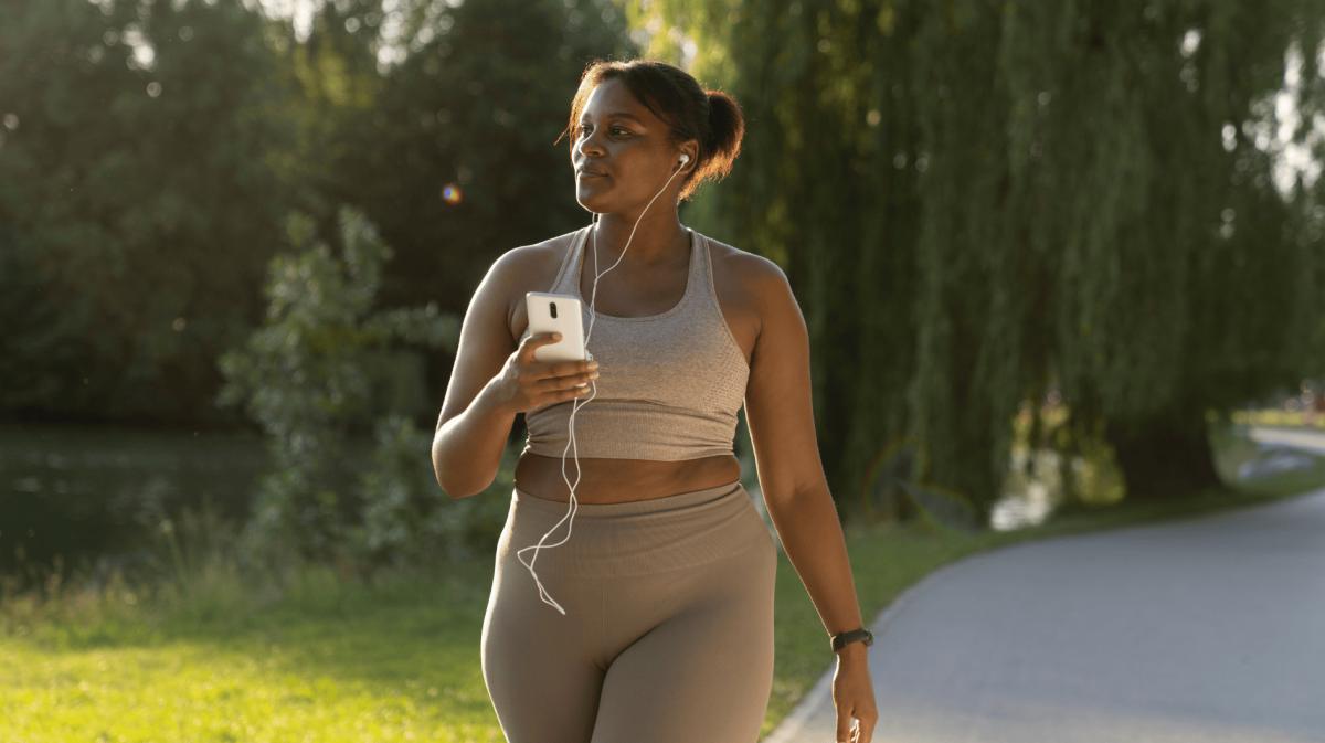 Junge, Schwarze Frau spaziert in Sportkleidung draußen.