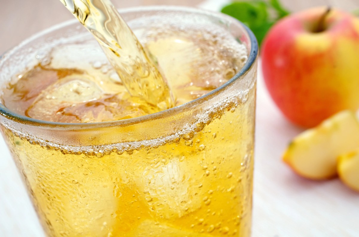 Apfelsaftschorle wir din ein Glas mit Eiswürfeln gegossen