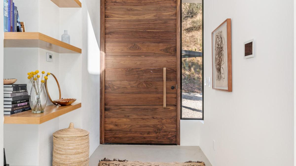 Stylischer Flur mit wertiger Holztür und edlem Regal.