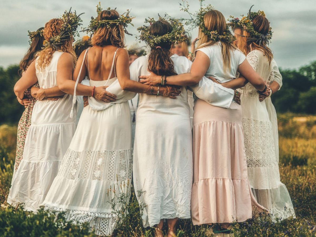 Frauen tanzen in wei&szlig;en Kleidern und mit Blumenkr&auml;nzen im Haar