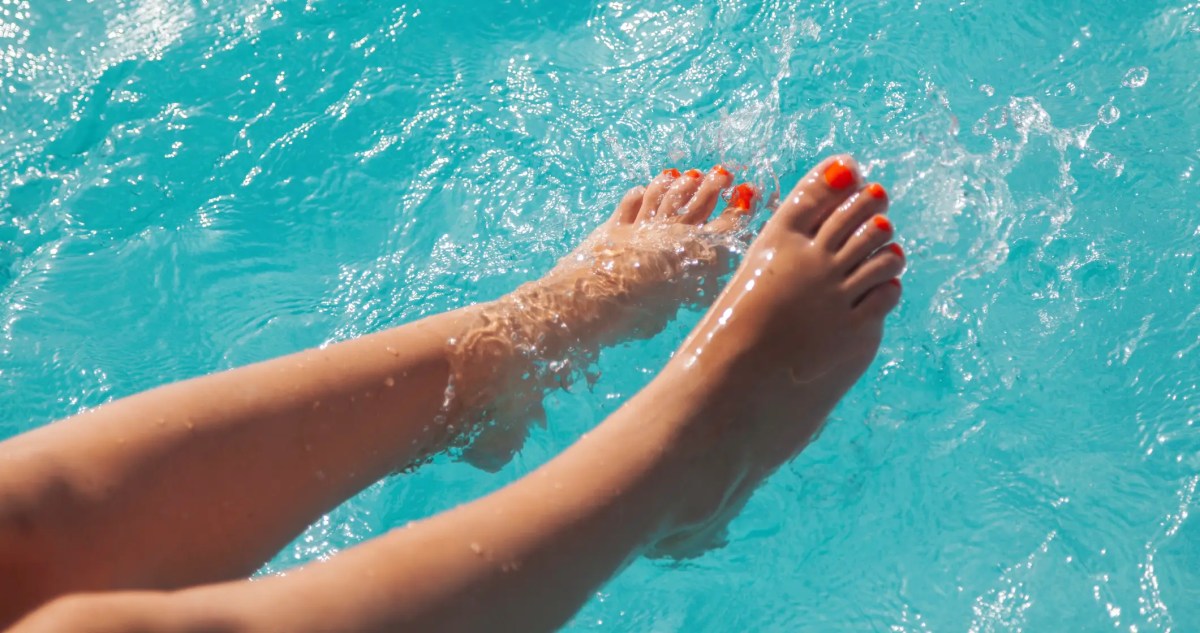 Füße mit rot lackierten Nägeln im Wasser