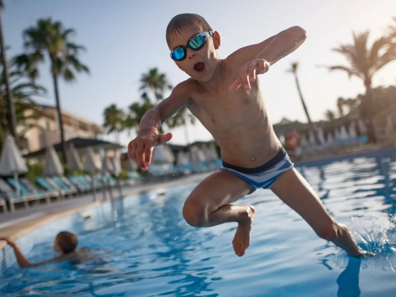 Junge, ca 7 Jahre alt, albert im Freibad herum.