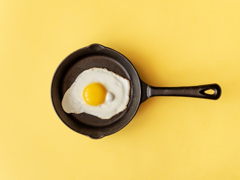 schwarze Pfanne mit Spiegelei auf gelbem Hintergrund