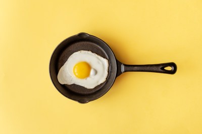 Diese geniale Funktion hat das Loch im Griff der Pfanne schwarze Pfanne mit Spiegelei auf gelbem Hintergrund