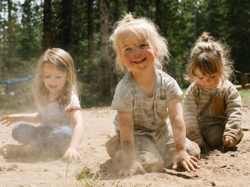 Drei fröhliche Mädchen spielen im Sand in einem Wald