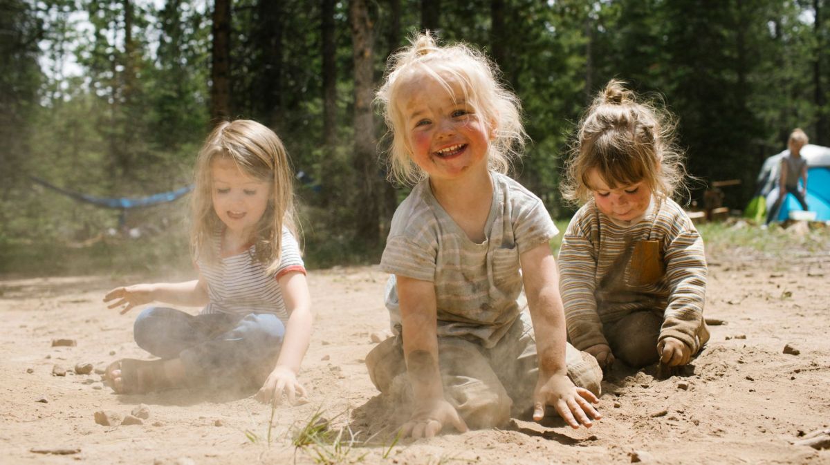 Drei fröhliche Mädchen spielen im Sand in einem Wald
