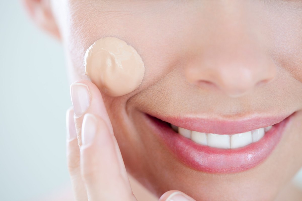 Frau mit einem Tropfen flüssigem Make-up im Gesicht