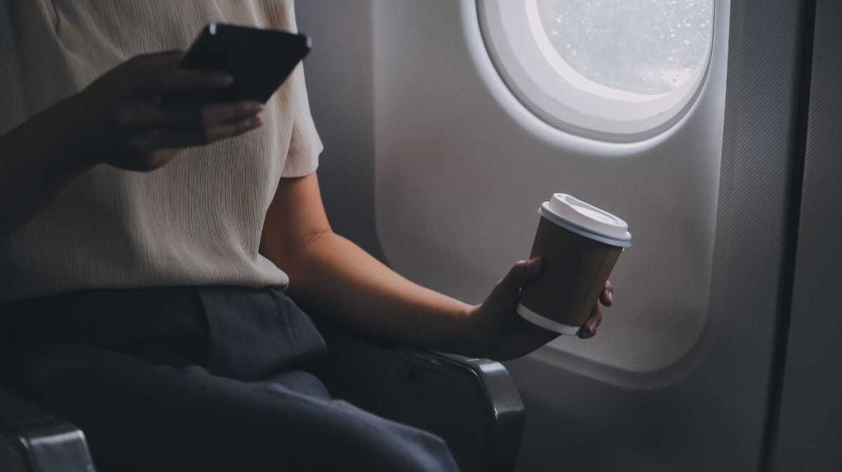 Frau im Flugzeug trinkt einen Kaffee
