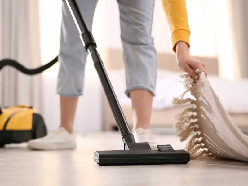 Frau saugt unter einem Teppich