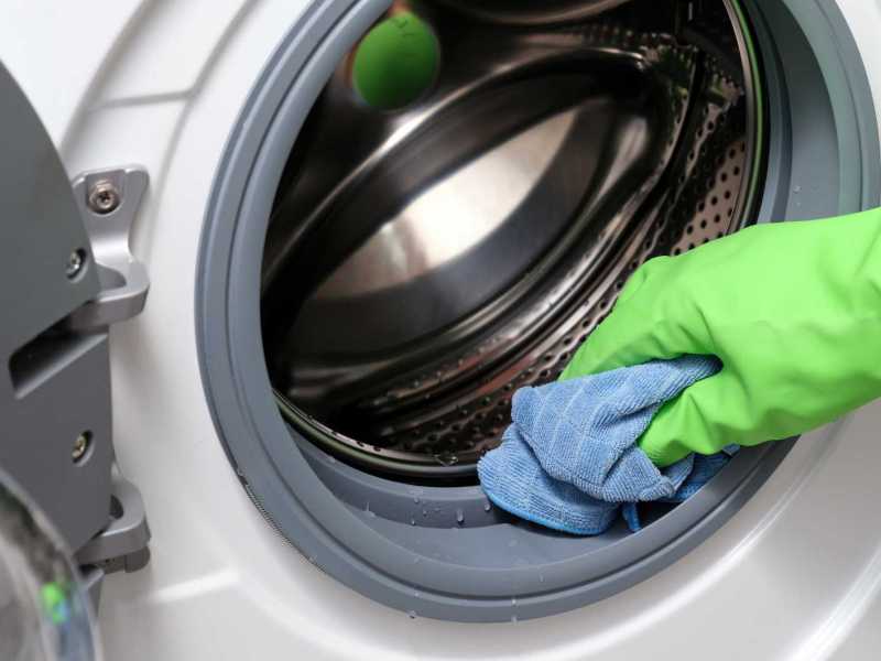 Dichtungen an der Waschmaschine werden mit einem Lappen abgewischt