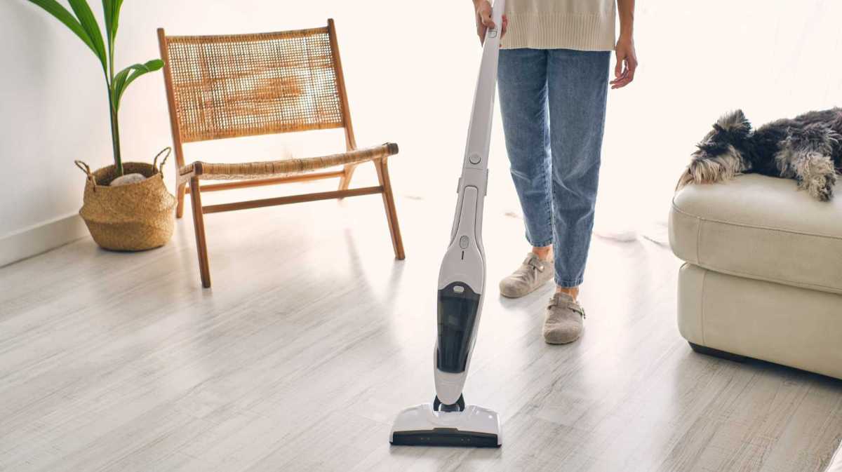 Mann saugt seinen Boden mit einem Staubsauger