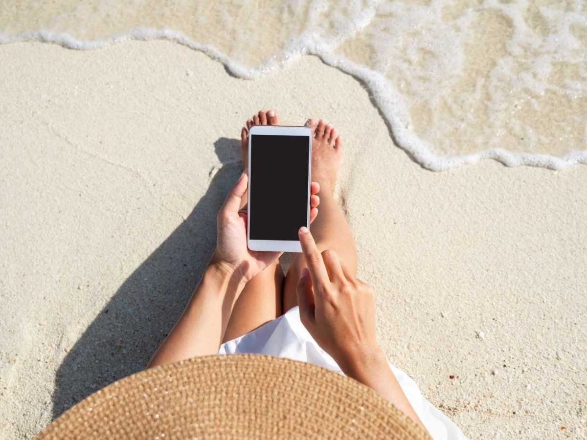 Frau benutzt ihr Handy am Strand