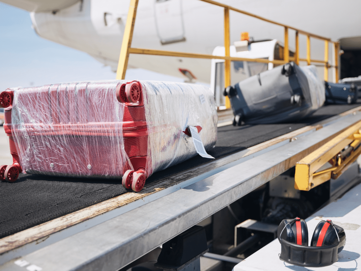 Mehrere Koffer in Folie gewickelt auf einem Gepäckband