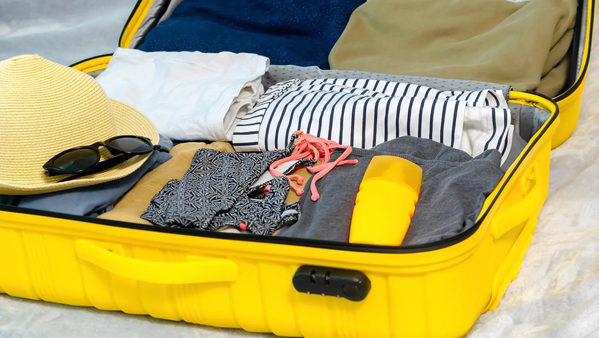 Vollgepackter Koffer mit Kleidung und Sonnencreme