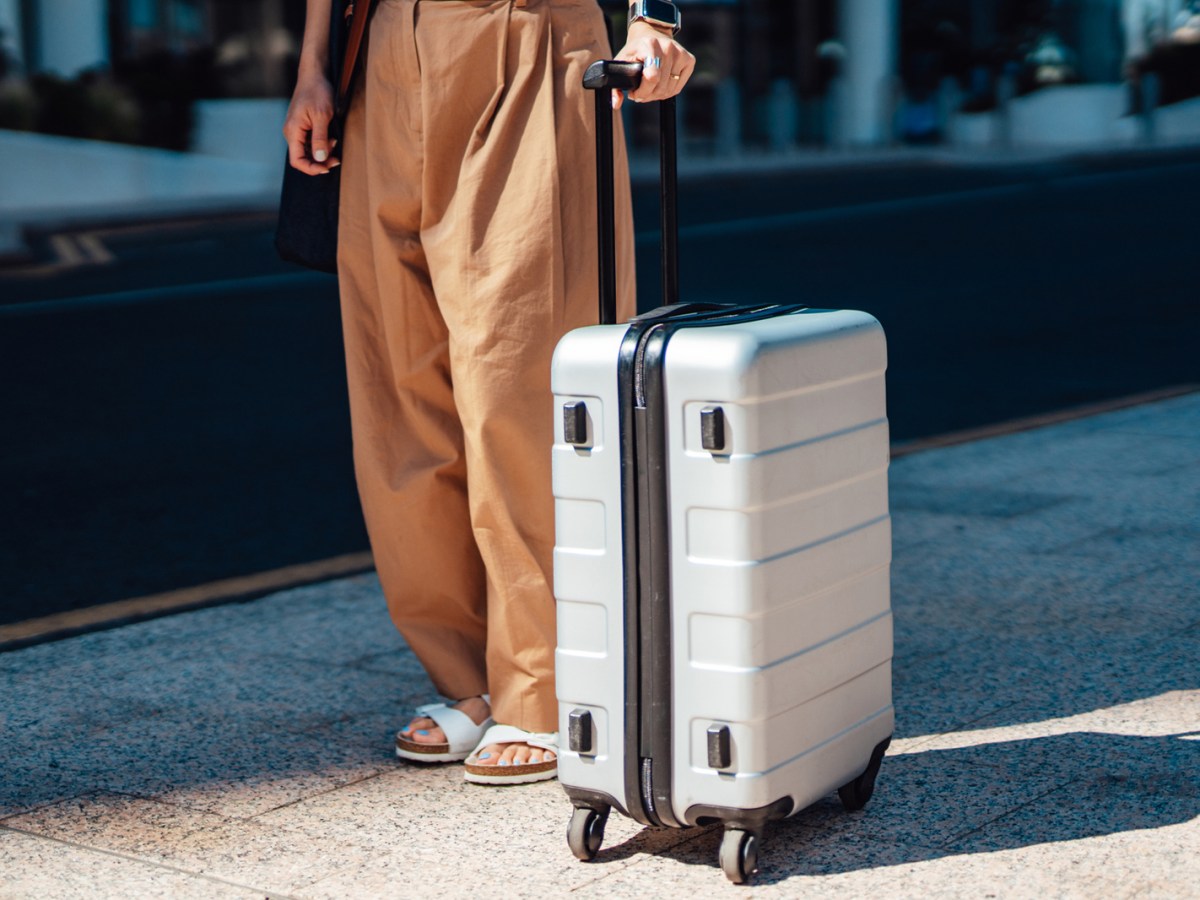 Frau steht mit Koffer am Bahsteig