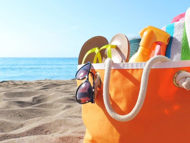 Strandtasche in Orange steht am Strand.