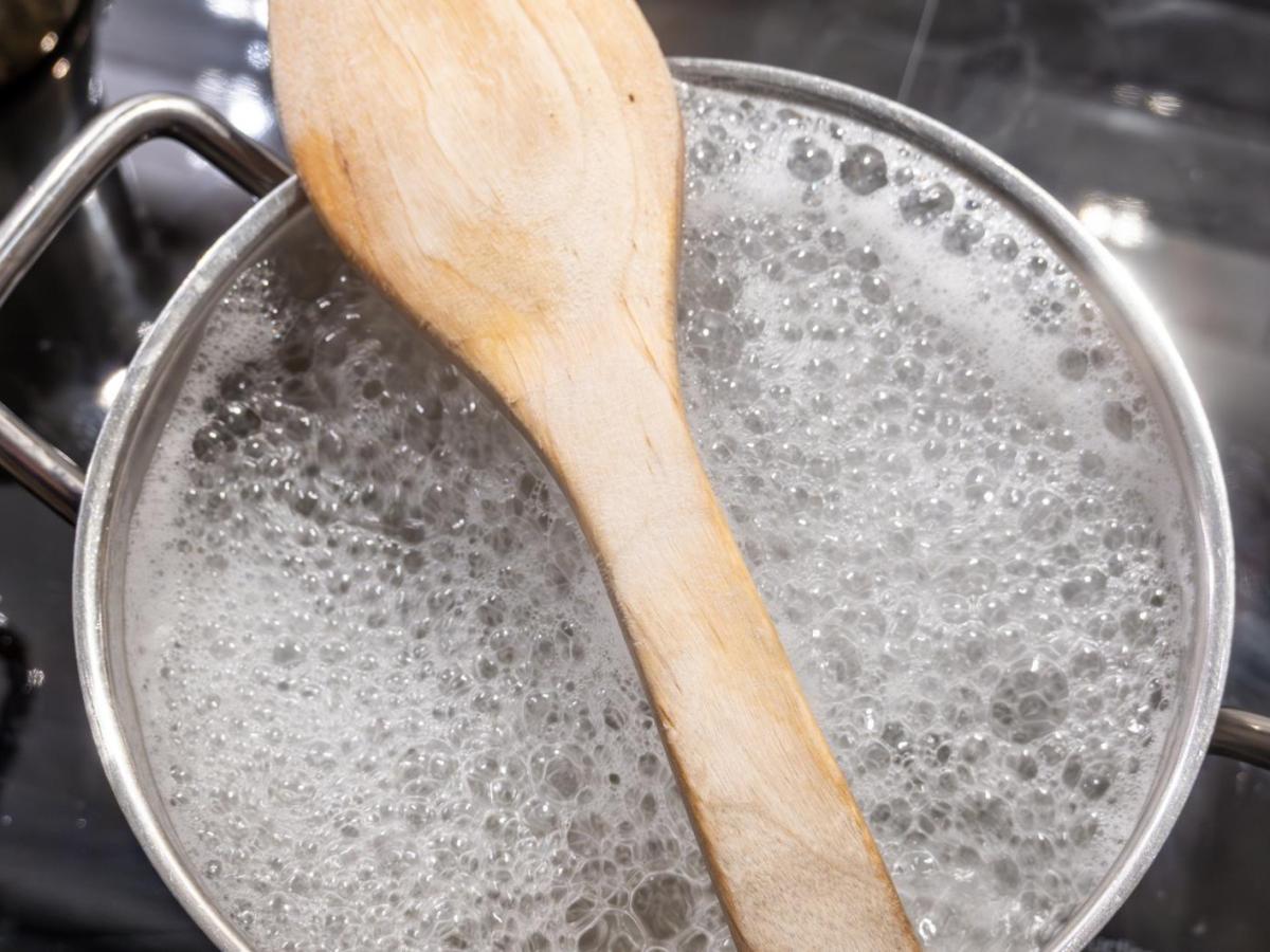 Holzl&ouml;ffel liegt auf einem Topf mit kochendem Wasser.