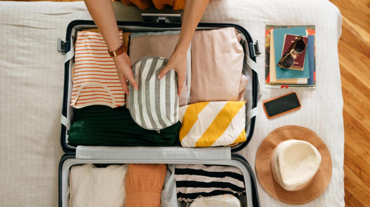 Frau packt einen Koffer für den Urlaub.