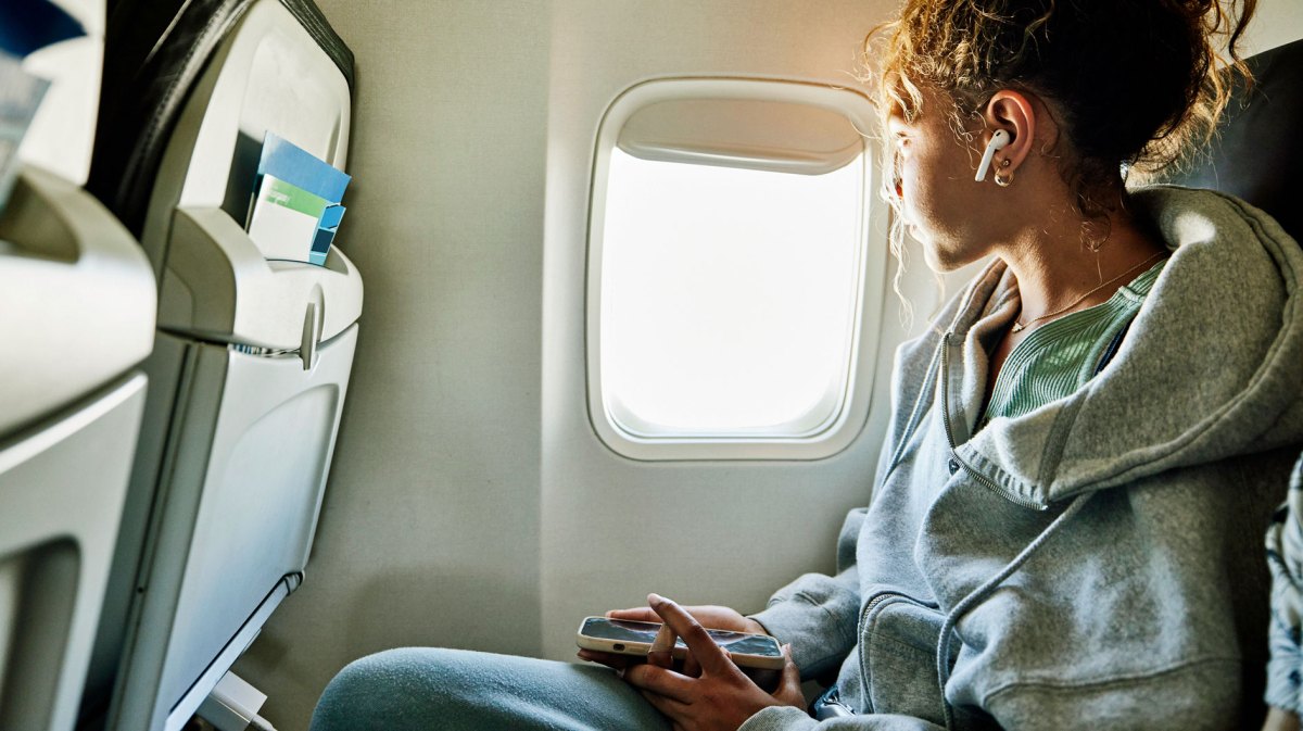 Frau im Flugzeug mit Handy in der Hand