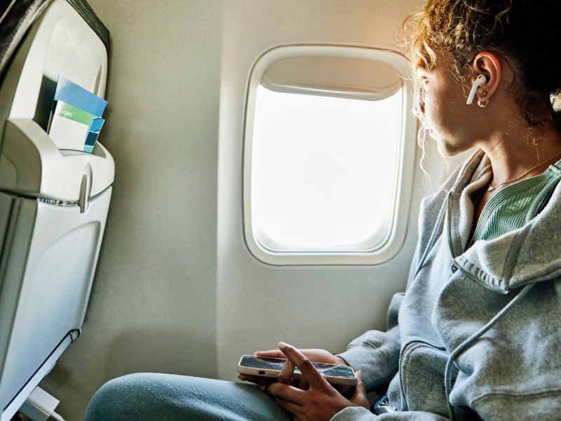 Frau im Flugzeug mit Handy in der Hand