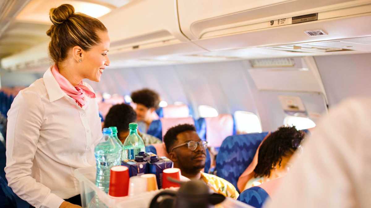 Flugbegleiterin mit Trolley im Flugzeug.