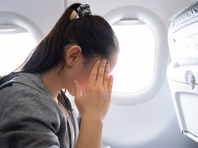Frau mit Händen am Gesicht in Flugzeug