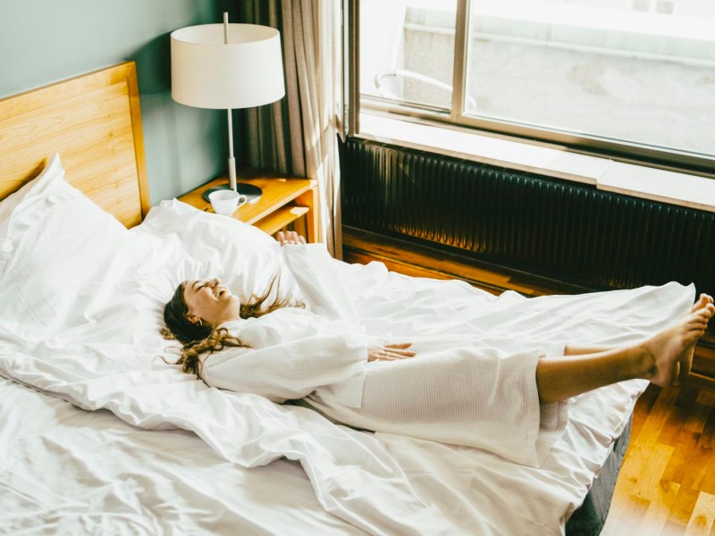 Frau lässt sich im Hotel aufs Bett fallen