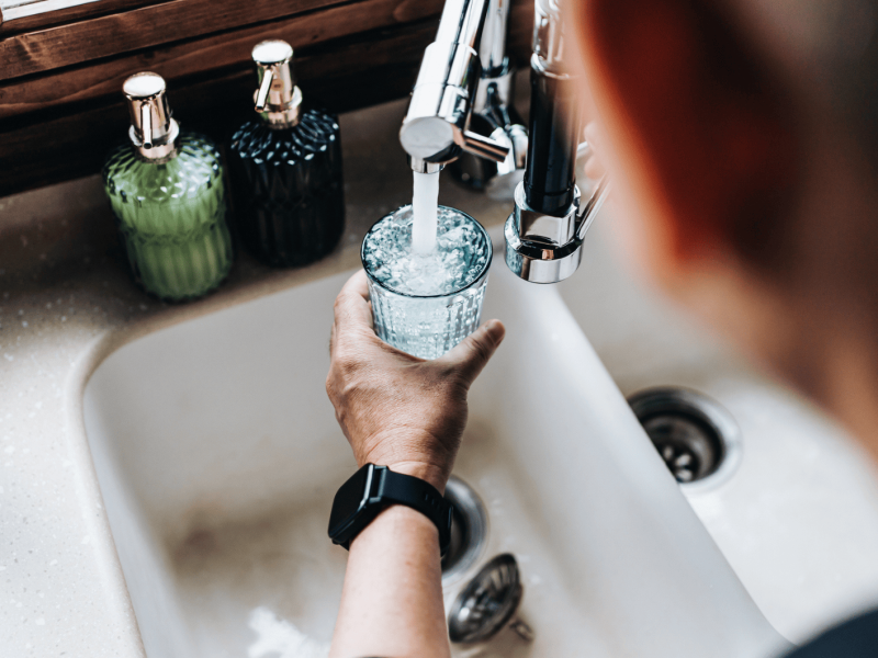 Mann füllt Wasser aus Hahn in Glas.