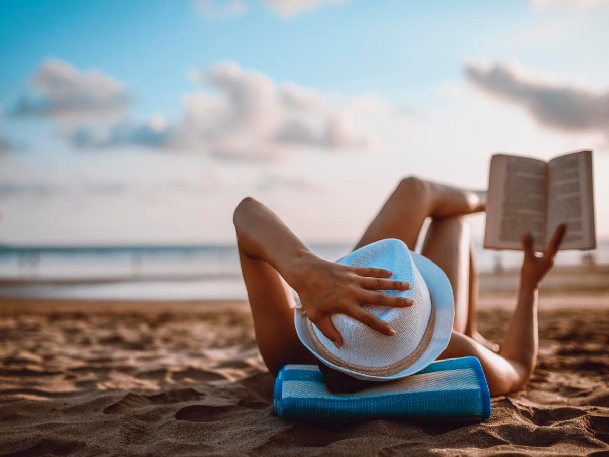 Frau liest entspannt am Strand