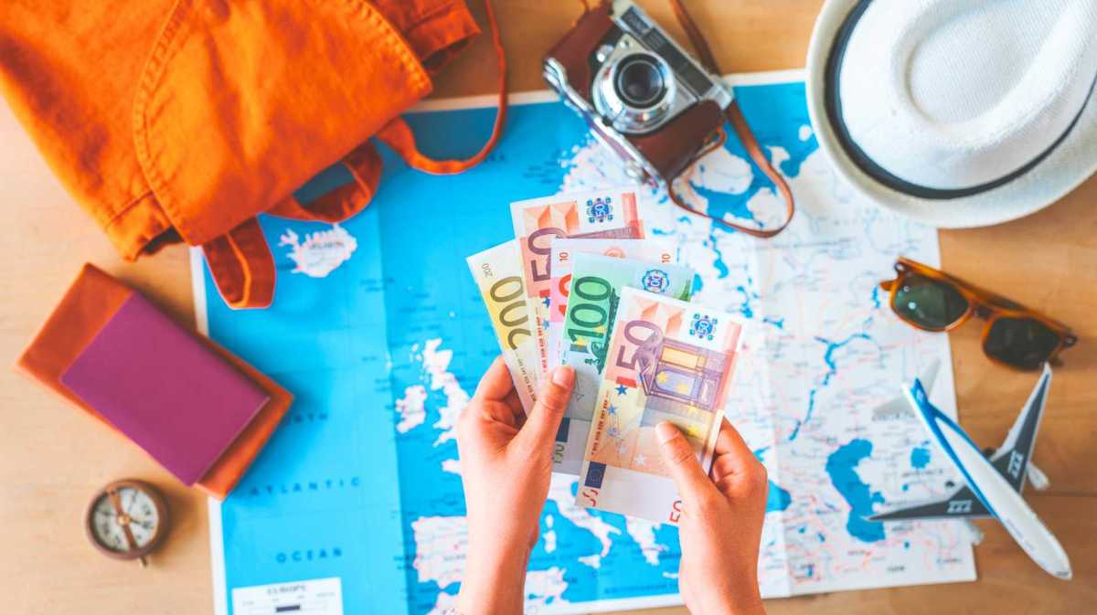 Frau hält Geld auf Reisehintergrund.